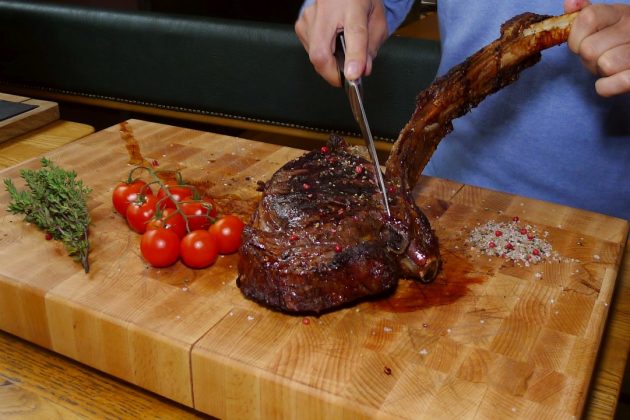 Flatschers · Tomahawk Steak wird beim Gast aufgeschnitten